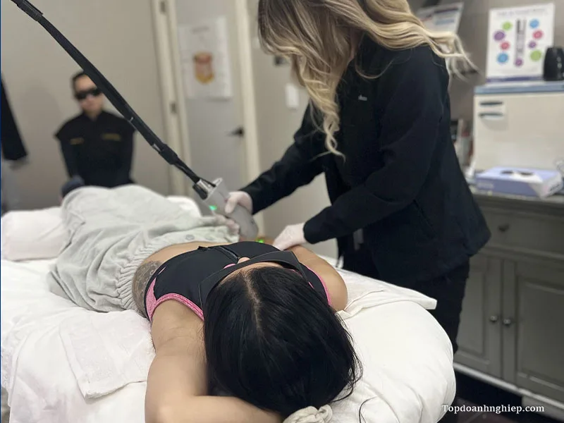 Practitioner operating an advanced laser treatment device on a client lying on a spa table