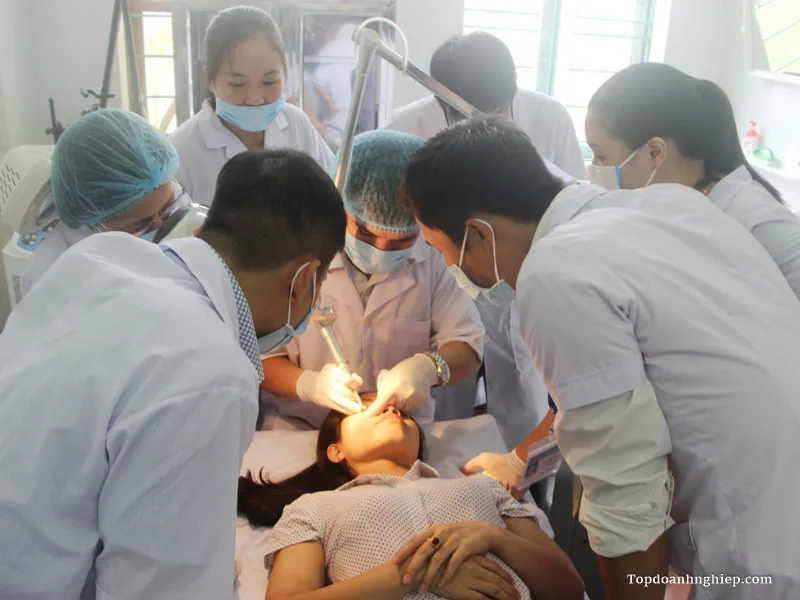Nhóm y bác sĩ đeo khẩu trang quây quần tập trung thực hiện thao tác kỹ thuật laser trị liệu cho khách hàng