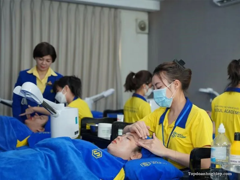 Students wearing yellow uniforms practicing hands-on facial and aesthetic techniques at Seoul Academy