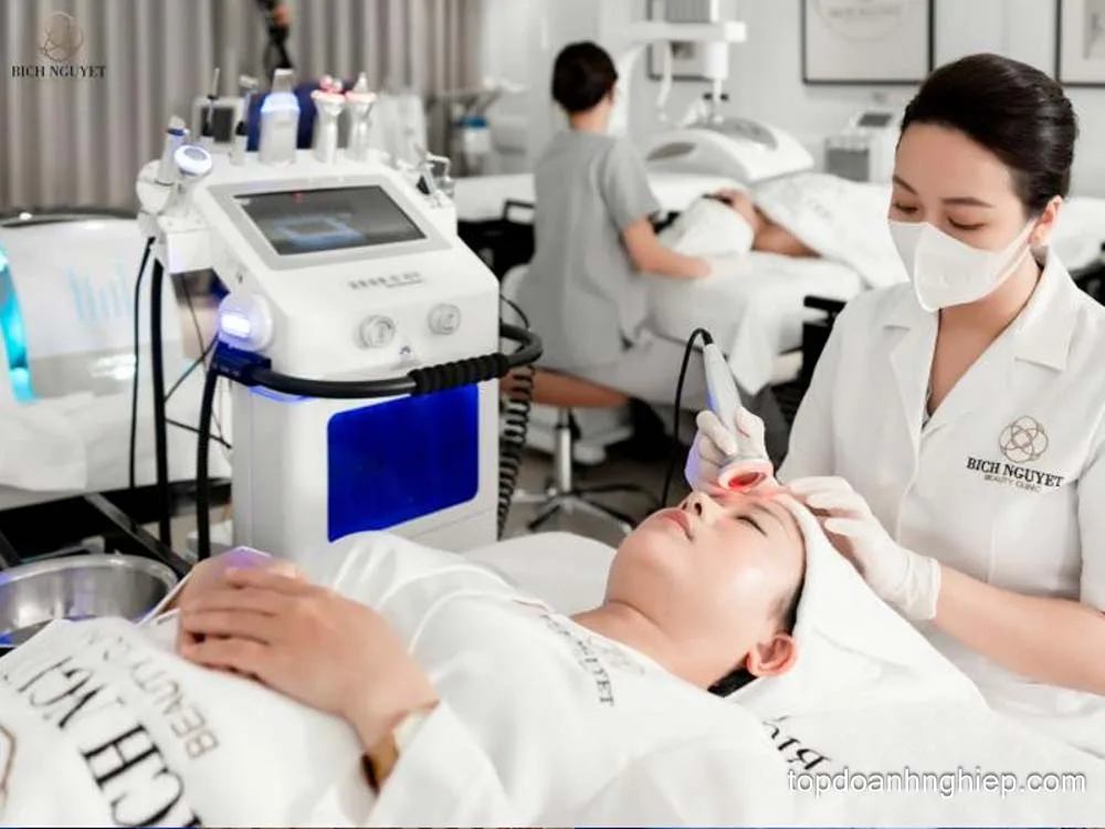 Aesthetician wearing a protective mask using a skin therapy device on a client at Bich Nguyet Beauty Clinic